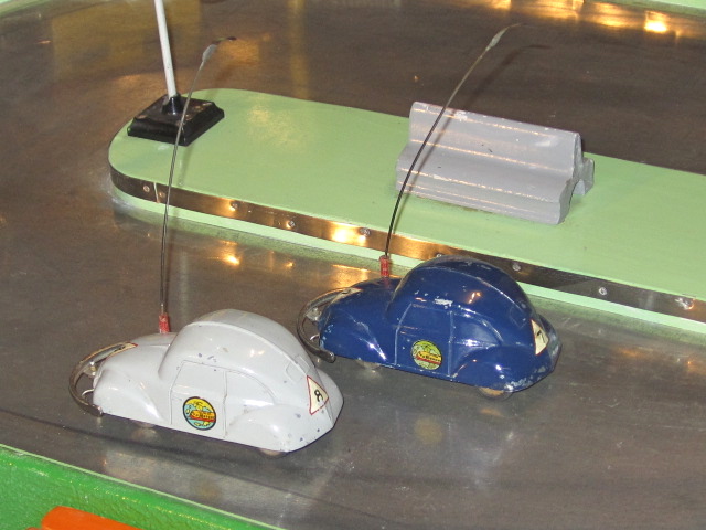 2 CARS RACING ON THE TRACK. THE FRONT WHEELS & THE ANTENNA CONDUCTED THE ELECTRIC CURRENT.