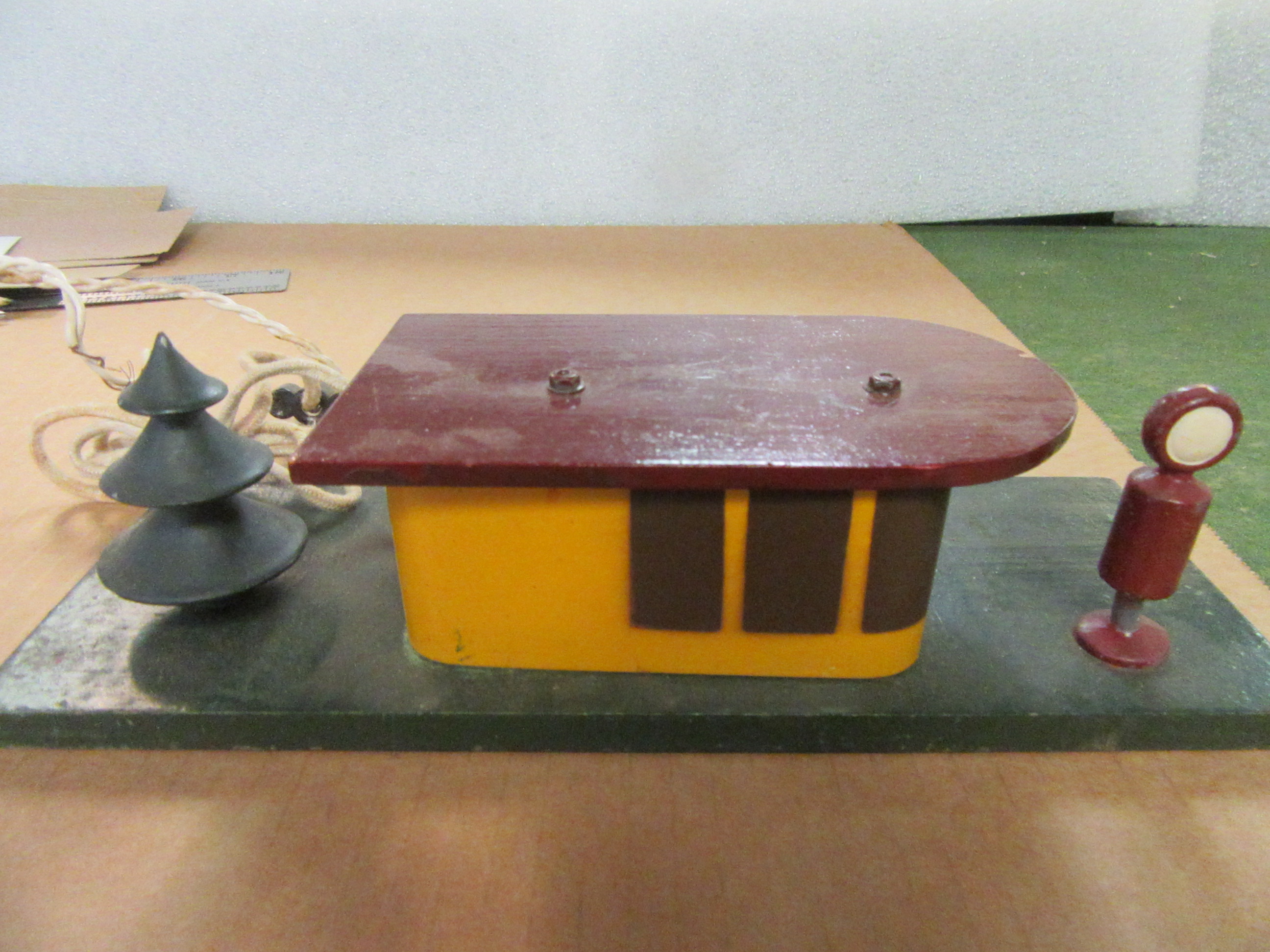 WOOD & SHEET METAL GAS STATION CONTAINING THE TRANSFORMER, A WOOD TREE, & A GAS PUMP.